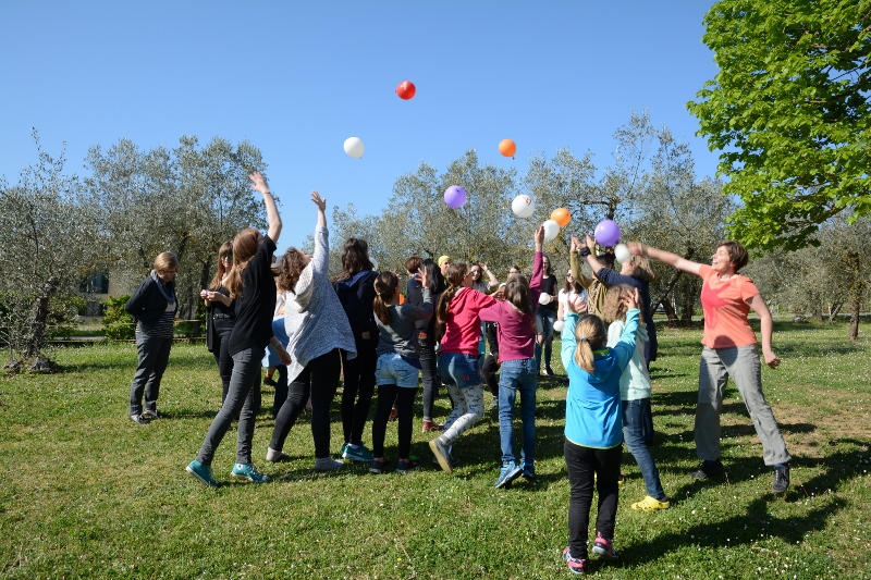 Jugendliche und Kinder die mit Luftballons auf einer Wiese spielen.