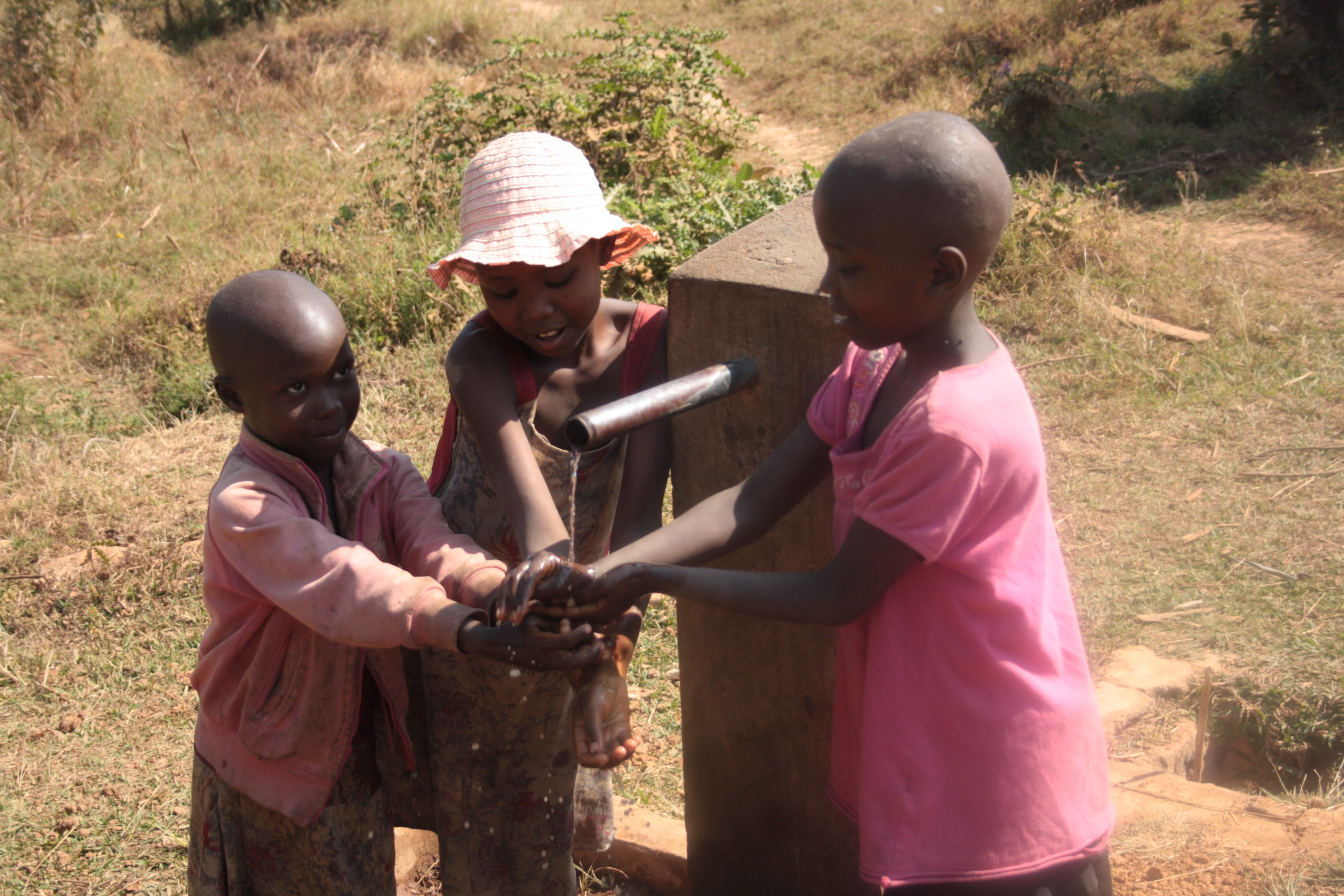 Kinder des Partnerprojekts in Burundi bei einem Brunnen